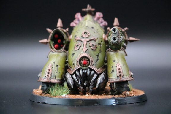 A detailed miniature model of a green, spiky sci-fi creature with weapon pylons.